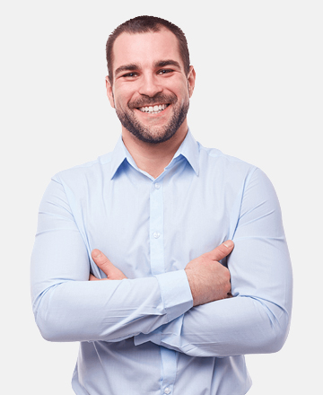 A smiling man with his arms crossed. He is wearing a light blue, long-sleeved collared shirt. The background is plain white.  The overall impression is one of confidence and approachability.